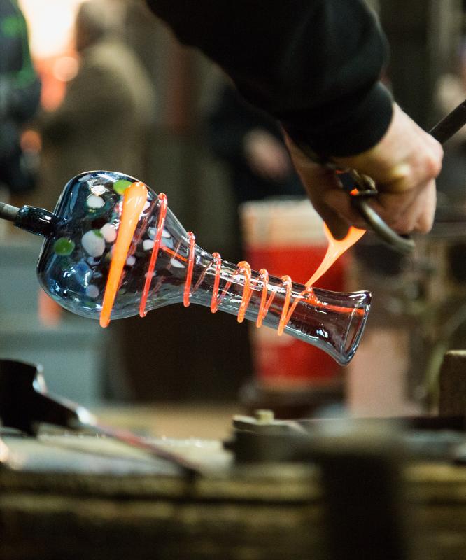A glassmaker finishing a vase by hand